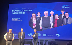 Bilateral AI is presented on stage with an image of the BilAI Board of Directors.