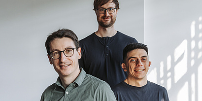 Image of the team of Emmi AI Johannes Brandstetter, Dennis Just, Miks Mikelsons smiling towards the camera.