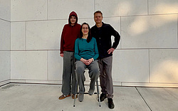 A boy, a woman and a man standing together, smiling at the camera.