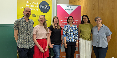 female researchers of the BIlAI project standing in front of event roll up