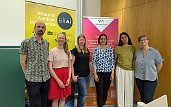 female researchers of the BIlAI project standing in front of event roll up