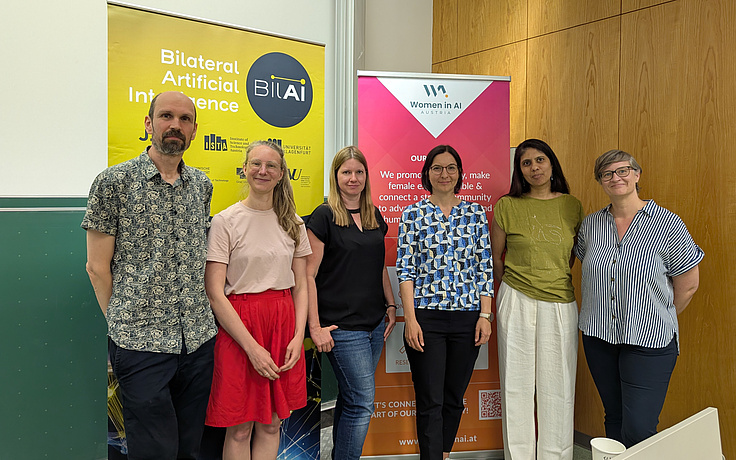 female researchers of the BIlAI project standing in front of event roll up