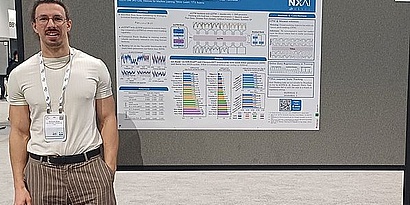Researcher at NEURIPS, standing in front of a scientific poster.