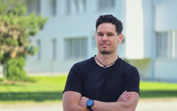 Researcher Patrick Rodler with dark hair  and dark t-shirt smiling at the camera.