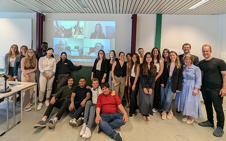 The group of global business master students all around Marcella Krawinkler, Univ-Prof. Dr. Robert Breitenecker and Univ-Prof. Robert Legenstein smiling in the camera.
