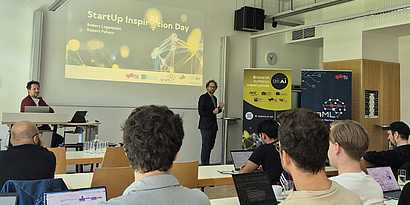 Robert Peharz standing in front of the audience, referring to the StartUp INspirAItion Day, giving a keynote.