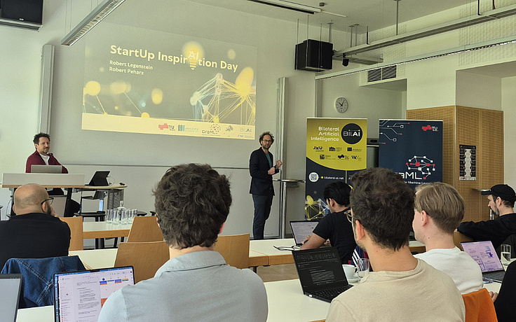 Robert Peharz standing in front of the audience, referring to the StartUp INspirAItion Day, giving a keynote.